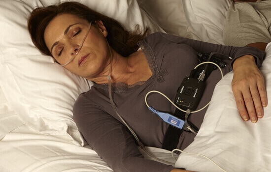 A woman sleeping during a sleep study, with sensors attached to her body.