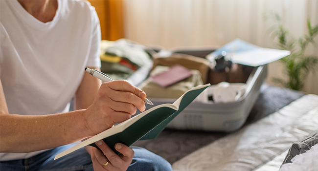  Traveler preparing a packing checklist next to an open suitcase, ensuring CPAP device and essentials are ready for a stress-free journey