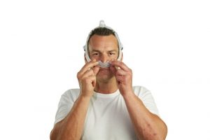 British Man fits nasal CPAP mask on his face
