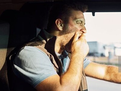 Exhausted driver yawning while driving a truck.