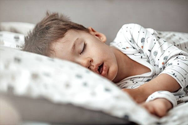 A child snoring and sleeping with mouth open on a blanket