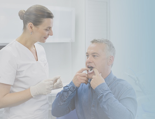 A female dentist watching as her male patient inserts the Narval CC into his mouth