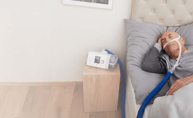 A man sleeping in bed while receiving home high-flow therapy treatment