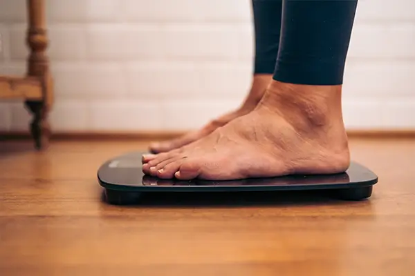 A pair of feet on some bathroom scales as someone weighs themself to check their BMI.