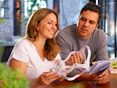 A woman looking at her new ResMed CPAP mask with her partner