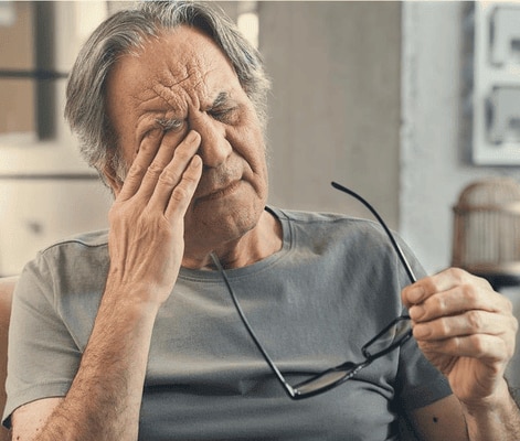  Older man rubbing his eye, looking tired